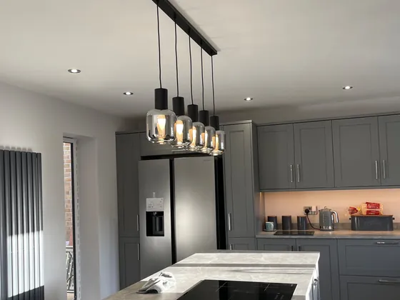 Kitchen island with a row of glass pendant lights over the hob